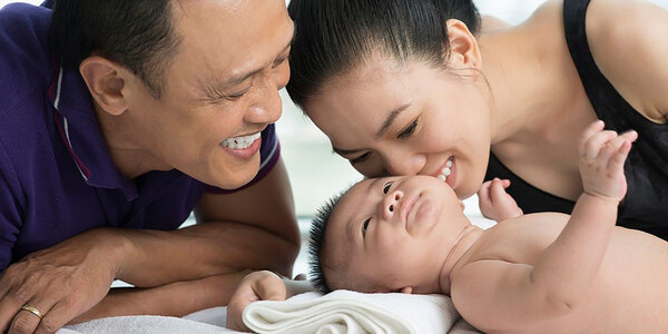 new parents and baby on bed