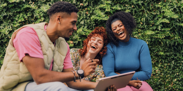 young people on park bench with computer