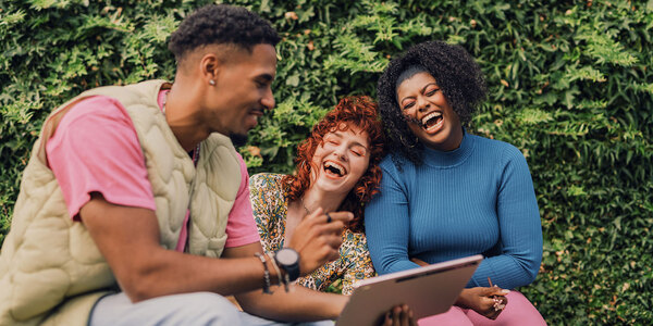 young people on park bench with computer